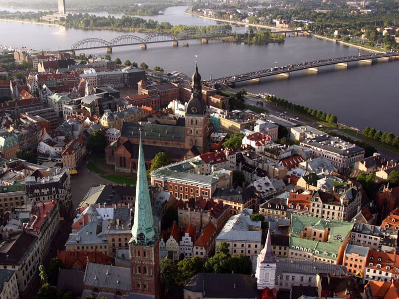 Aerial view of a historic city centre with a prominent church and river in the background.