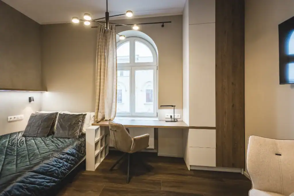 Modern studio apartment with workspace and large window in city center.