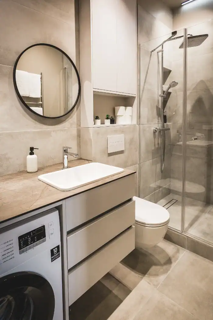 Bright bathroom with shower, sink, and washing machine in compact studio near Central Station.