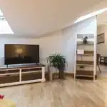 Bright living room with TV, bookshelf, and wooden flooring in apartment.