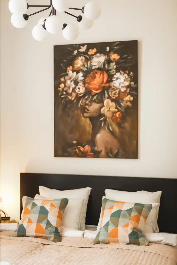 Bedroom interior with floral artwork, stylish cushions, and contemporary decor in Riga apartment.