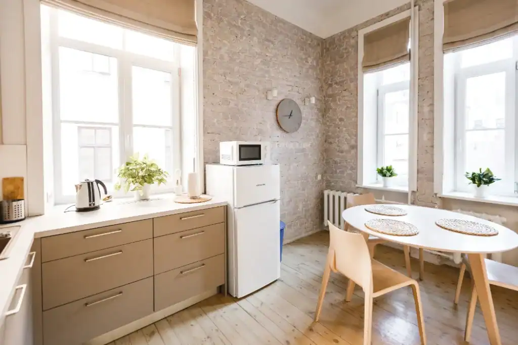 Bright kitchen with beige cabinets, white appliances, and dining area.